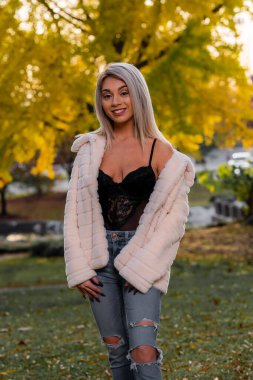 Genç ve güzel bir sarışın model, bir sonbahar gününün tadını çıkarırken dışarıda poz veriyor.