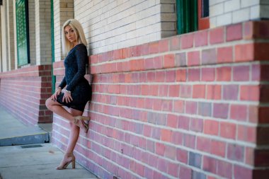 Sarışın bir model tren istasyonunda tren beklerken dışarıda poz veriyor.