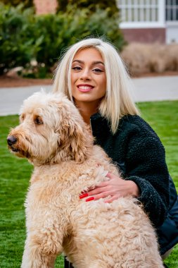 Sarışın bir manken yavru köpeğiyle dışarıda poz veriyor.