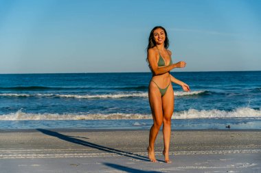 Güzel bir melez bikini modeli sahilde açık havanın tadını çıkarıyor.