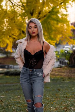 Genç ve güzel bir sarışın model, bir sonbahar gününün tadını çıkarırken dışarıda poz veriyor.