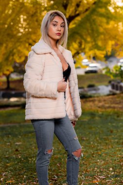 Genç ve güzel bir sarışın model, bir sonbahar gününün tadını çıkarırken dışarıda poz veriyor.