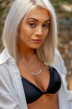 Sarışın bir bikini mankeni yaz gününün tadını çıkarırken dışarıda poz verir.