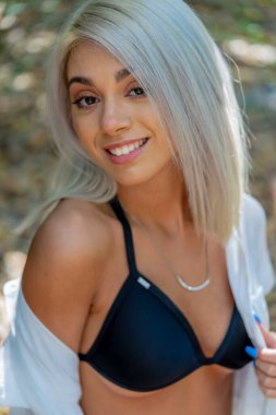 Sarışın bir bikini mankeni yaz gününün tadını çıkarırken dışarıda poz verir.