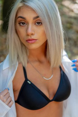 Sarışın bir bikini mankeni yaz gününün tadını çıkarırken dışarıda poz verir.