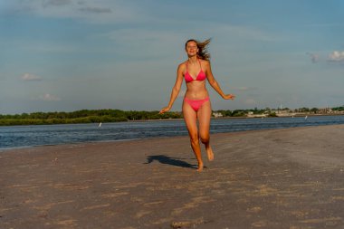 Güzel sarışın bir bikini mankeni sahilde açık havanın tadını çıkarıyor.