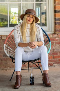 Sonbahar kıyafetleriyle dışarıda poz veren güzel bir sarışın manken.