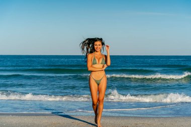 Güzel bir melez bikini modeli sahilde açık havanın tadını çıkarıyor.