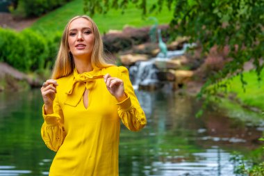 Sonbahar kıyafetleriyle dışarıda poz veren güzel bir sarışın manken.