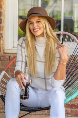 Sonbahar kıyafetleriyle dışarıda poz veren güzel bir sarışın manken.