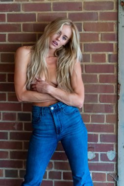 Sarışın bir manken dışarıda üstsüz poz veriyor.