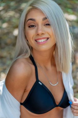 Sarışın bir bikini mankeni yaz gününün tadını çıkarırken dışarıda poz verir.