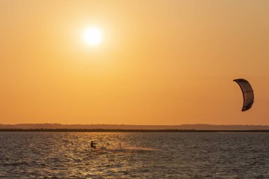 Profesyonel uçurtma sörfçüsünün deniz dalgasında akrobatik atlayışı. Sporcu, uçurtma ve havada sörf yaparak atlama numarası yapıyor. Ekstrem su sporları ve yaz tatili konsepti