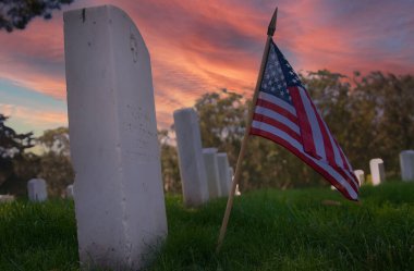 Askeri mezarlıkta ölen bir kahramanın önünde küçük bir Amerikan bayrağı duruyor.