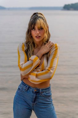 Muhteşem bir esmer model göl kenarındaki yaz havasının tadını çıkarıyor.