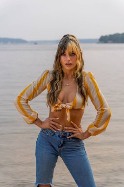 Muhteşem bir esmer model göl kenarındaki yaz havasının tadını çıkarıyor.