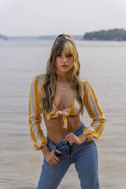 Muhteşem bir esmer model göl kenarındaki yaz havasının tadını çıkarıyor.