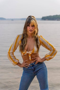 Muhteşem bir esmer model göl kenarındaki yaz havasının tadını çıkarıyor.