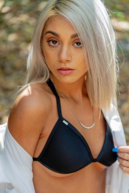 Sarışın bir bikini mankeni yaz gününün tadını çıkarırken dışarıda poz verir.