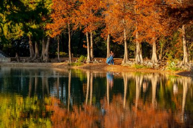 Muhteşem bir esmer model, sonbahar havasının tadını çıkarırken dışarıda poz veriyor.