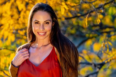 Muhteşem bir esmer model, sonbahar havasının tadını çıkarırken dışarıda poz veriyor.