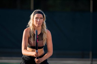 Sarışın bir model tenis kortunda öğleden sonra güneşinde tenis oynuyor.