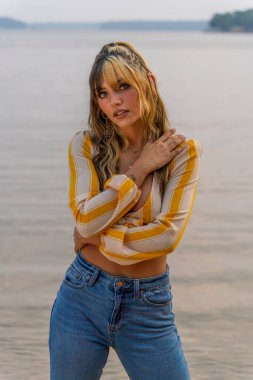 Muhteşem bir esmer model göl kenarındaki yaz havasının tadını çıkarıyor.