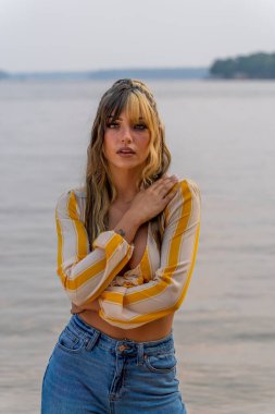 Muhteşem bir esmer model göl kenarındaki yaz havasının tadını çıkarıyor.