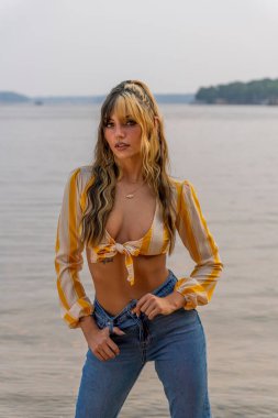 Muhteşem bir esmer model göl kenarındaki yaz havasının tadını çıkarıyor.