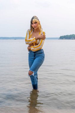 Muhteşem bir esmer model göl kenarındaki yaz havasının tadını çıkarıyor.