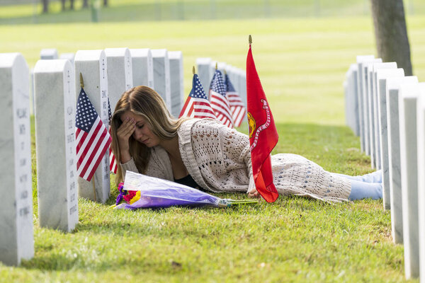 A young bride shows her grief at the burial site of a family member at a military cemetery