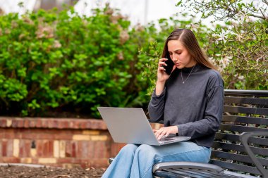 Muhteşem bir esmer model, bahar havasının tadını çıkarırken bilgisayarında çalışıyor.