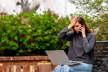 Muhteşem bir esmer model, bahar havasının tadını çıkarırken bilgisayarında çalışıyor.