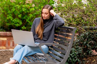 Muhteşem bir esmer model, bahar havasının tadını çıkarırken bilgisayarında çalışıyor.