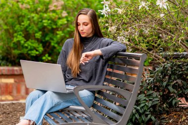 Muhteşem bir esmer model, bahar havasının tadını çıkarırken bilgisayarında çalışıyor.
