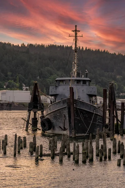 A old abandoned vessel sits on the dock near a river