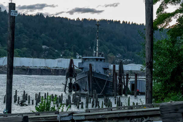 A old abandoned vessel sits on the dock near a river