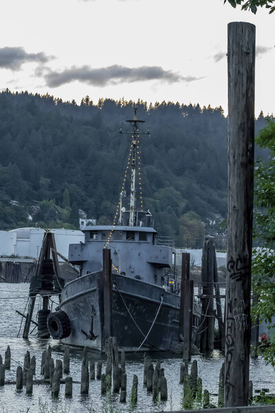 A old abandoned vessel sits on the dock near a river