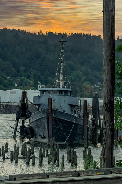 A old abandoned vessel sits on the dock near a river