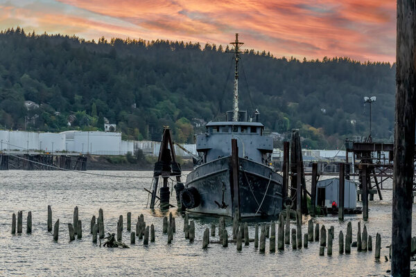 A old abandoned vessel sits on the dock near a river
