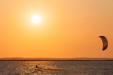 Profesyonel uçurtma sörfçüsünün deniz dalgasında akrobatik atlayışı. Sporcu, uçurtma ve havada sörf yaparak atlama numarası yapıyor. Ekstrem su sporları ve yaz tatili konsepti