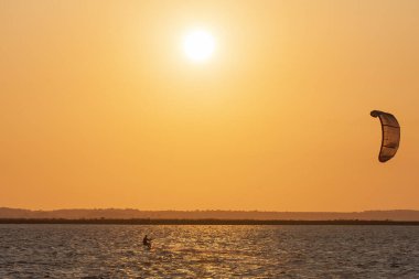 Profesyonel uçurtma sörfçüsünün deniz dalgasında akrobatik atlayışı. Sporcu, uçurtma ve havada sörf yaparak atlama numarası yapıyor. Ekstrem su sporları ve yaz tatili konsepti