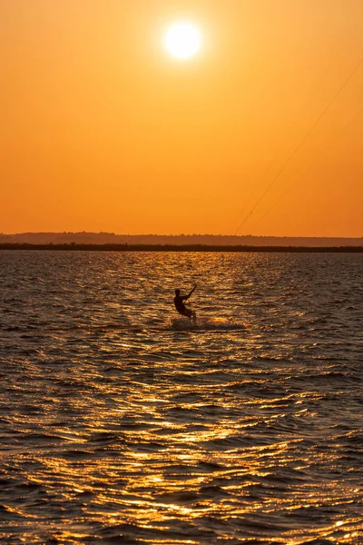 Acrobatic jump of professional kite surfer on the sea wave, athlete showing sport trick jumping with kite and board in air. Extreme water sport and summer vacations concept