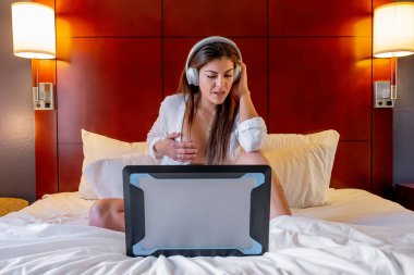Güzel bir İspanyol kadın bilgisayarla iletişim kuruyor ve yatak odası ortamında çıplak poz veriyor.