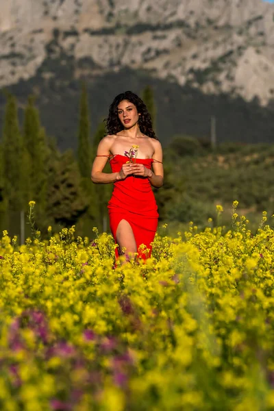 Çarpıcı bir Avrupalı model, İspanyol kır çiçeklerinin arasında yaz sonlarındaki parlaklığın tadını çıkarıyor. Doğanın güzelliğini zarafetle somutlaştırıyor..