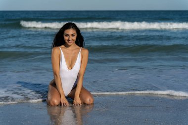 Göz kamaştırıcı melez bir bikini modeli güneşli bir plajda dinleniyor, parlayan tenini güneş öpüyor. Ferahlatıcı dalgaları, kendine güveni, zarafet ve güzellik saçan okyanus arkaplanını seviyor..