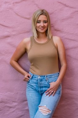 Güzel sarışın bir kadın ılık yaz güneşinde güneşleniyor, altın sarısı saçları gülümserken parlıyor, hafif rüzgarın ve günün canlı güzelliğinin tadını çıkarıyor..