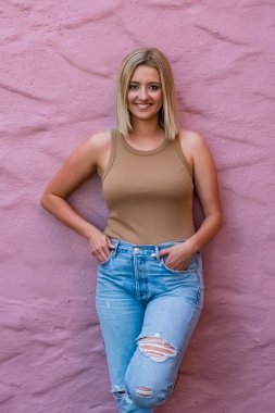 Güzel sarışın bir kadın ılık yaz güneşinde güneşleniyor, altın sarısı saçları gülümserken parlıyor, hafif rüzgarın ve günün canlı güzelliğinin tadını çıkarıyor..