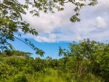 Bir rüzgar türbininin havadan görünüşü, açık alanlar üzerinde zarif bir şekilde dönen devasa bıçaklarının temiz ve yenilenebilir enerji üretmek ve fosil yakıtlara olan bağımlılığını azaltmak için rüzgar enerjisini kullandığını gösteriyor..