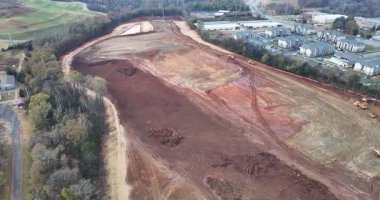 Buldozerler ve kazıcıların toprağı temizlediği, enkaz taşıyan kamyonların ve gelecekteki büyük depo yapılarının ana hatlarını belirleyen işaretli temellerin bulunduğu uçsuz bucaksız bir inşaat alanının havadan görüntüsü..